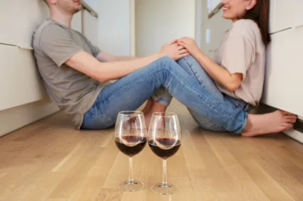 Ljubav i vino / Foto: freepik.com zaljubljeni par sedi na podu, a ispred njih dve čaše vina