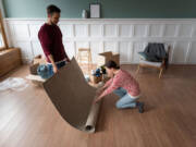 Mladi par postavlja tepih na podnu oblogu / foto: freepik.com