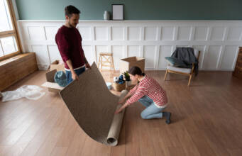 Mladi par postavlja tepih na podnu oblogu / foto: freepik.com